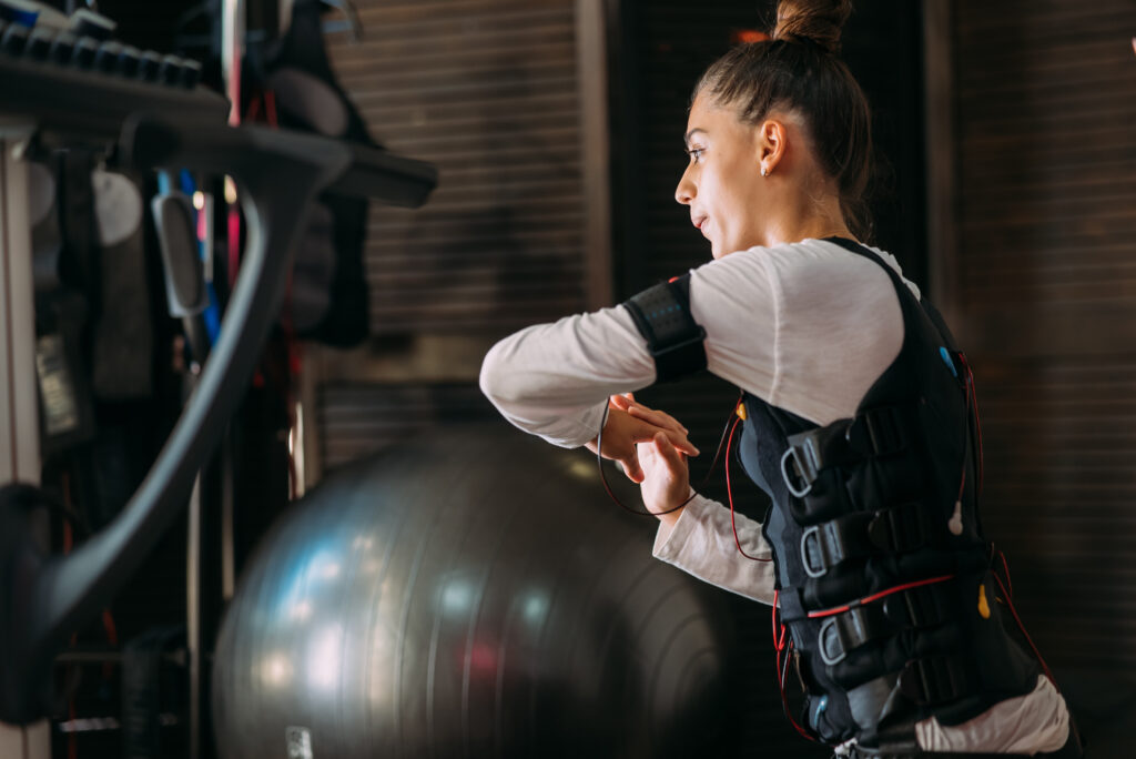 Woman training in a gym wearing an EMS suit, illustrating the EMS suits vs. the gym comparison.
