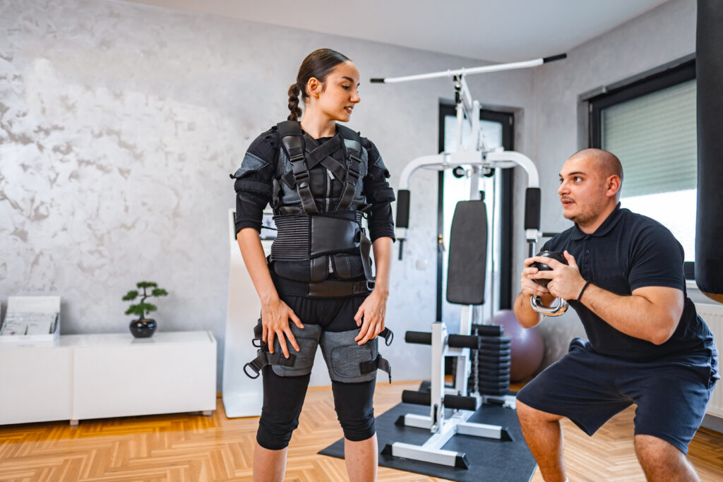 A woman in an EMS suit completing 20 minutes of EMS training with male trainer.