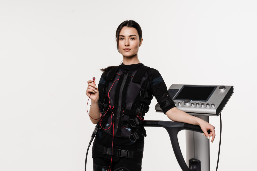 Modern EMS suit and machine showing how the history of electrical muscle stimulation has evolved into fitness technology.
