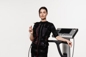 Modern EMS suit and machine showing how the history of electrical muscle stimulation has evolved into fitness technology.
