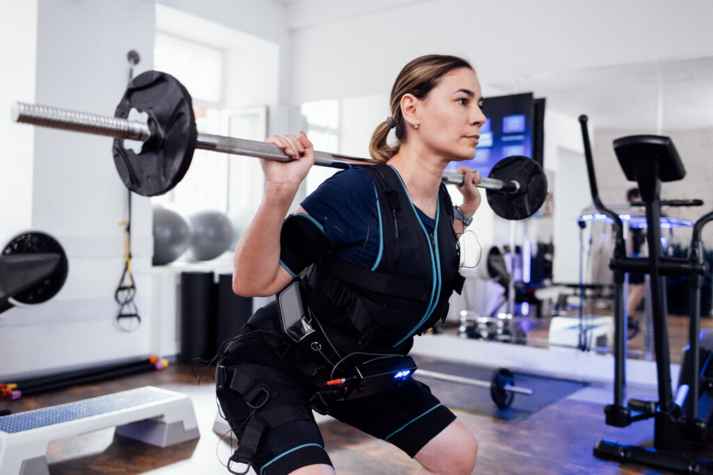 Woman in the best ems suit doing weight training.
