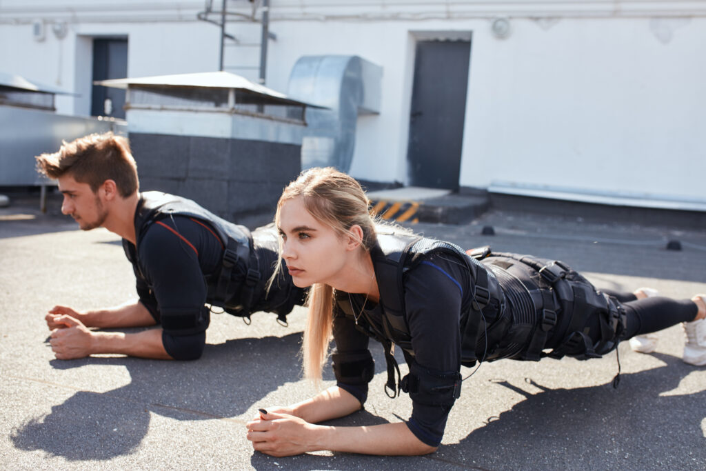 A man and woman doing planks in EMS body suits during EMS training.
